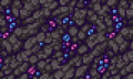 Mur de pierre bosselée avec des cristaux bleus et roses qui en sortent